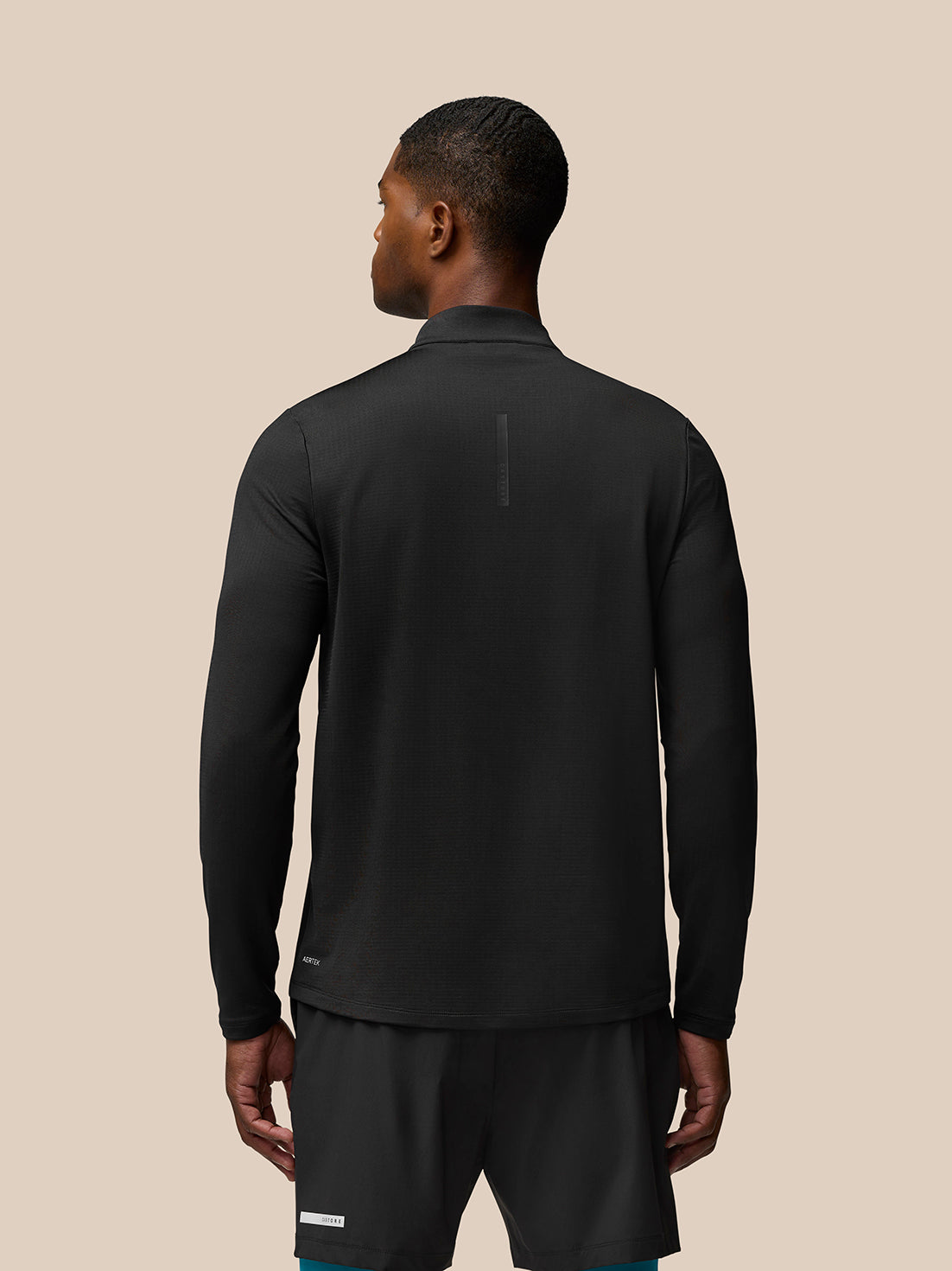 Back view of a man wearing Flow Sweatshirt Black with funnel collar and curved hem.