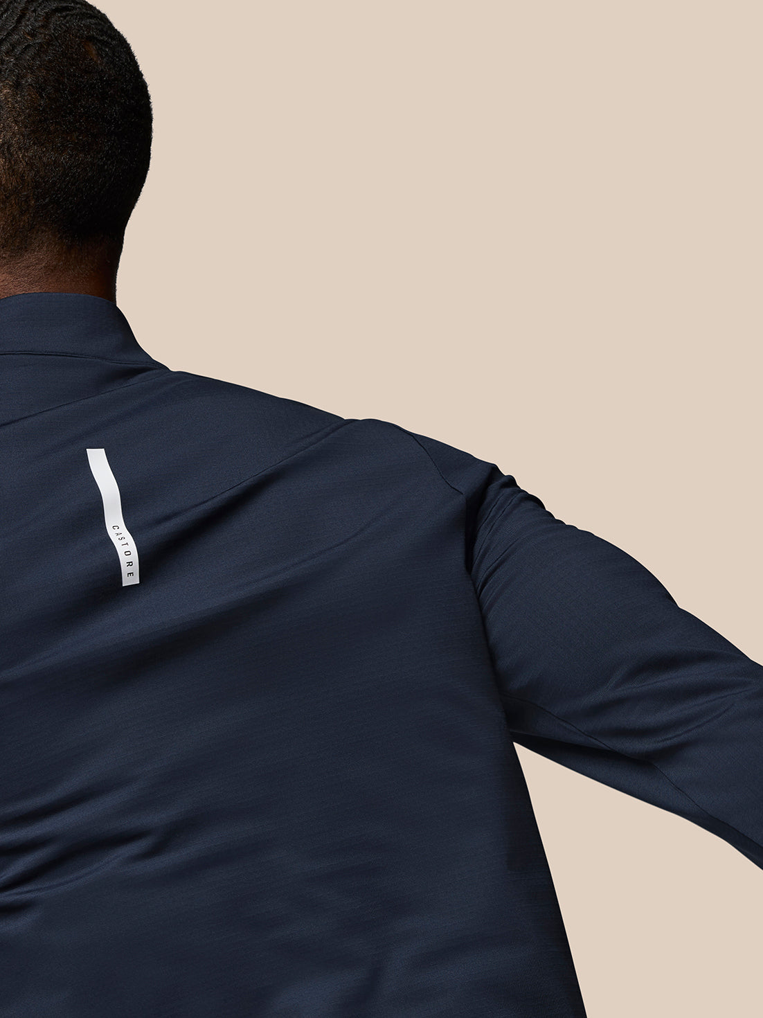 Back view of navy Flow Quarter Zip Sweater Top with white branding tag along the lower back