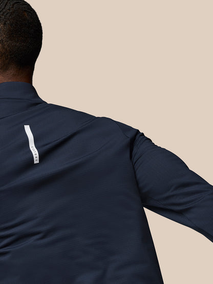 Back view of navy Flow Quarter Zip Sweater Top with white branding tag along the lower back