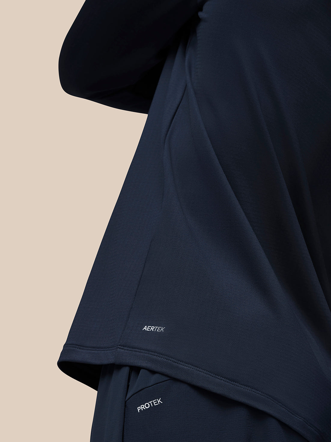Lower back detail of navy Flow Quarter Zip Sweater Top showing AERTEK imprint on the hem
