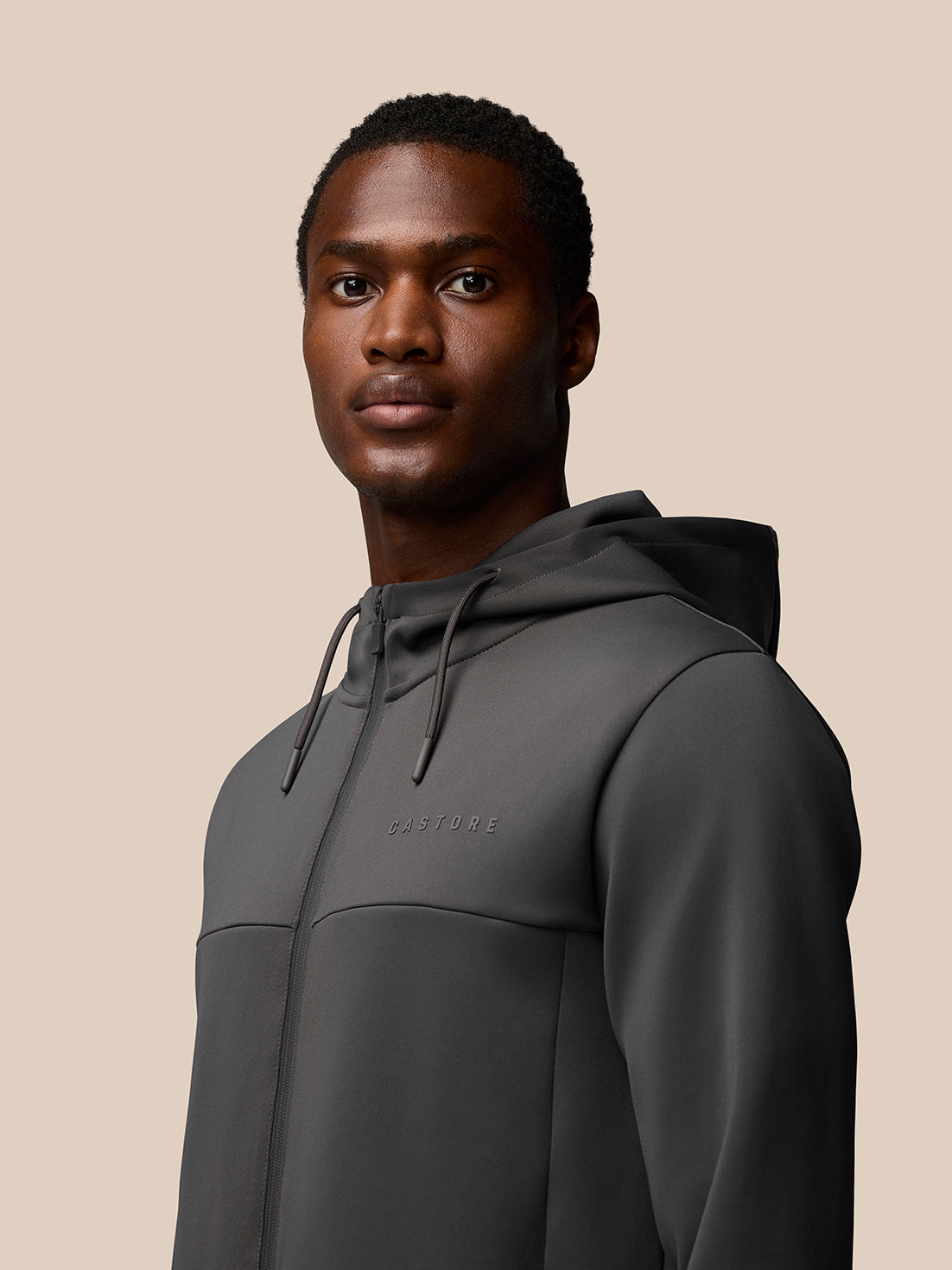 Male model wearing charcoal Flex Lifestyle Full Zip jacket with hood and Castore logo on chest.