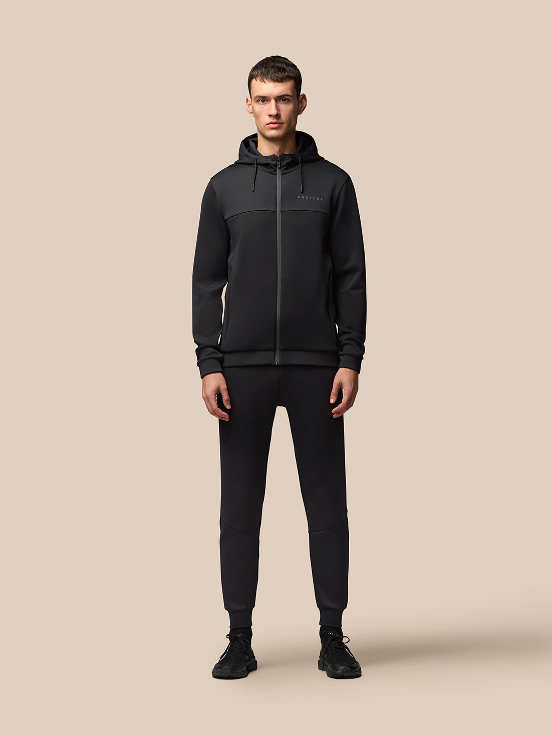 Male model wearing black Castore Flex Lifestyle full zip hooded jacket with front pockets