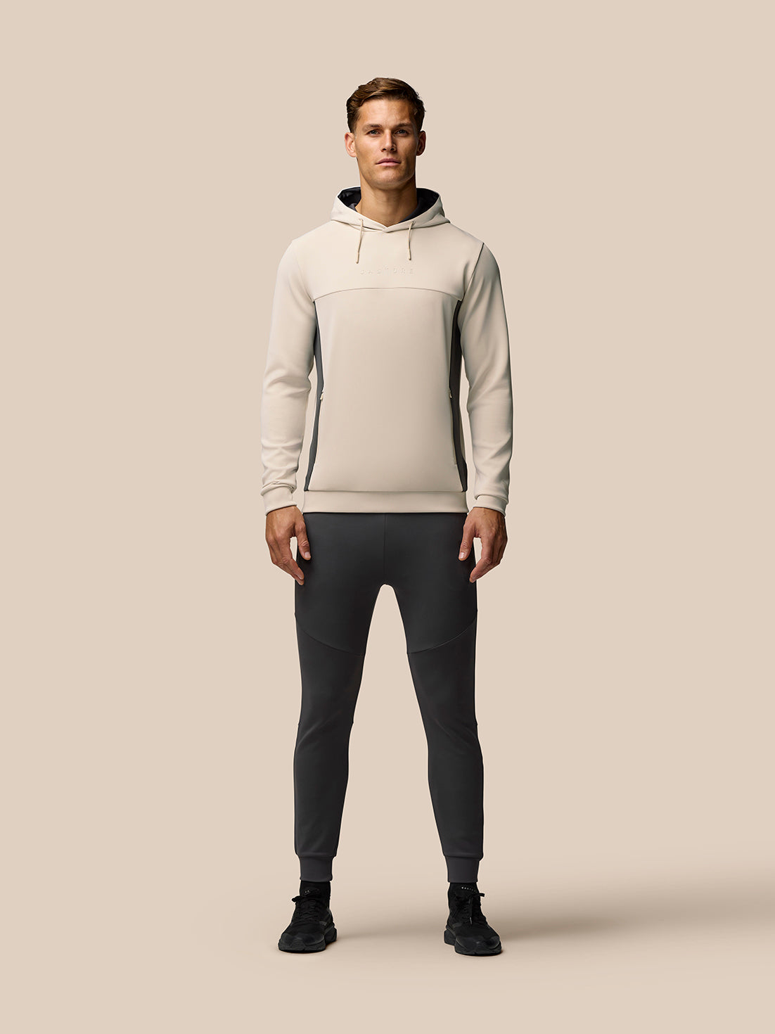 Male model wearing beige Flex Lifestyle Hoodie with contrast side panels and drawstring hood
