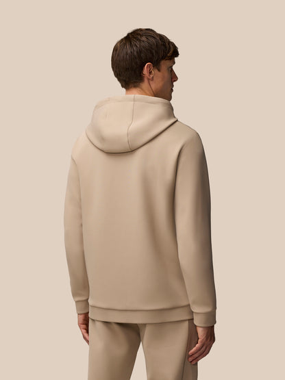 Male model in mushroom beige Flex Lifestyle Hoodie seen from the side with drawcord hood and zipped pocket.