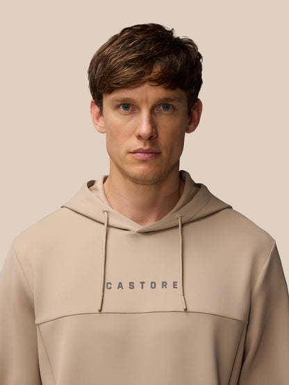 Model wearing mushroom beige Flex Lifestyle Hoodie with Castore wordmark on chest and ProTek branding on lower back.