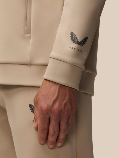 Close up of mushroom color Flex Lifestyle Hoodie sleeve with Castore wing logo on the forearm.