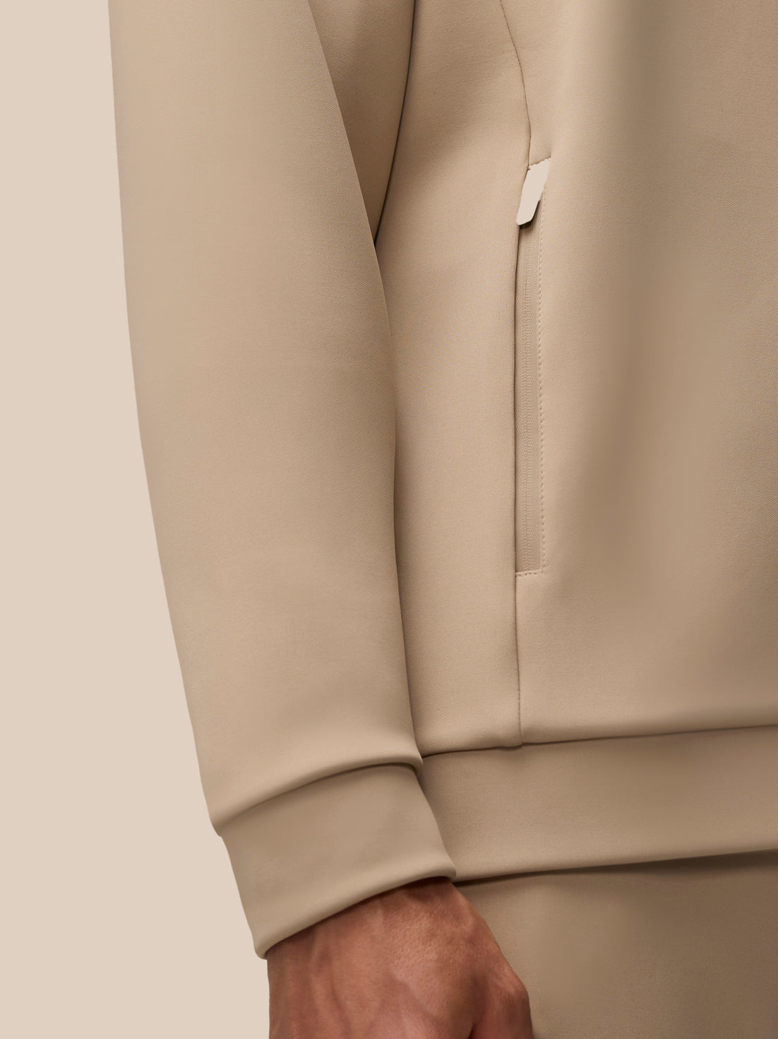 Beige Flex Lifestyle Hoodie side view highlighting a vertical zip pocket and cuff detail.