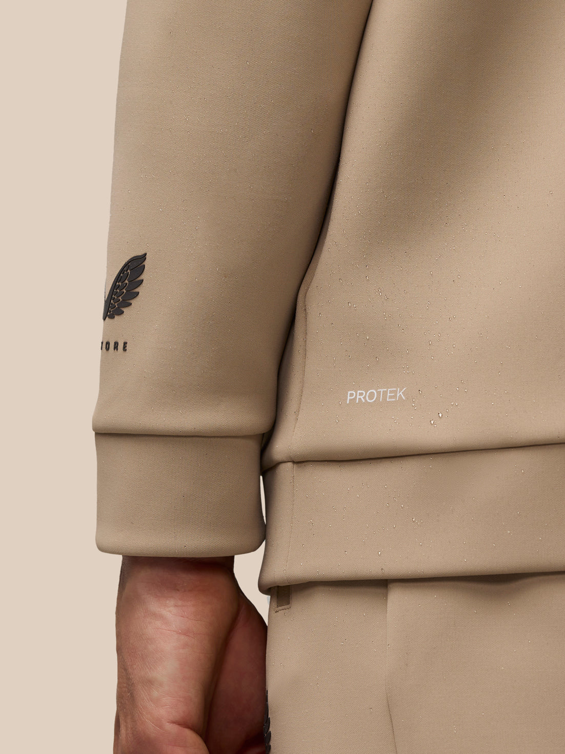 Close up of mushroom hoodie sleeve showing the winged Castore logo and ProTek branding.