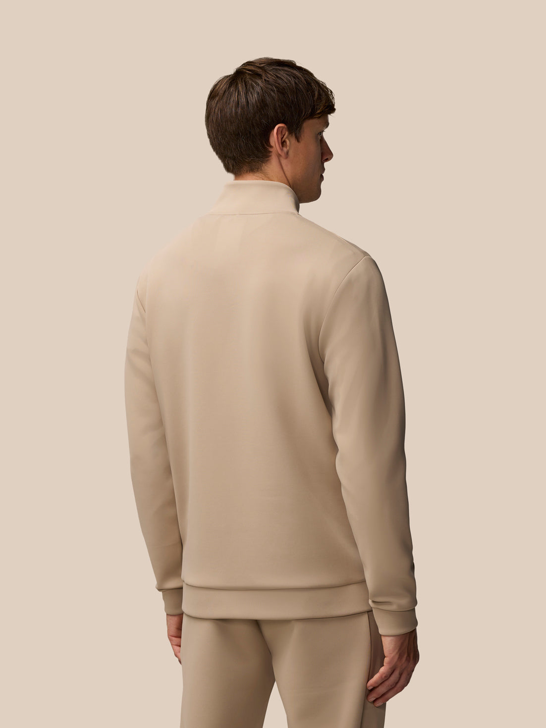 Back view of beige Castore Flex Lifestyle quarter zip top worn by a model