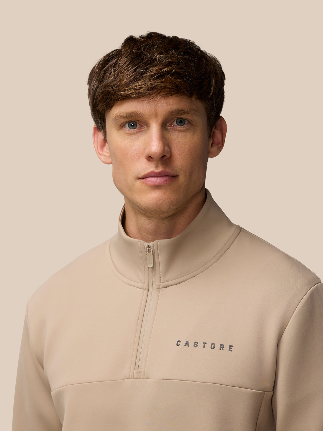 Model wearing Flex Lifestyle 1/4 Zip Mushroom Gunmetal with front zipper and Castore logo on the chest