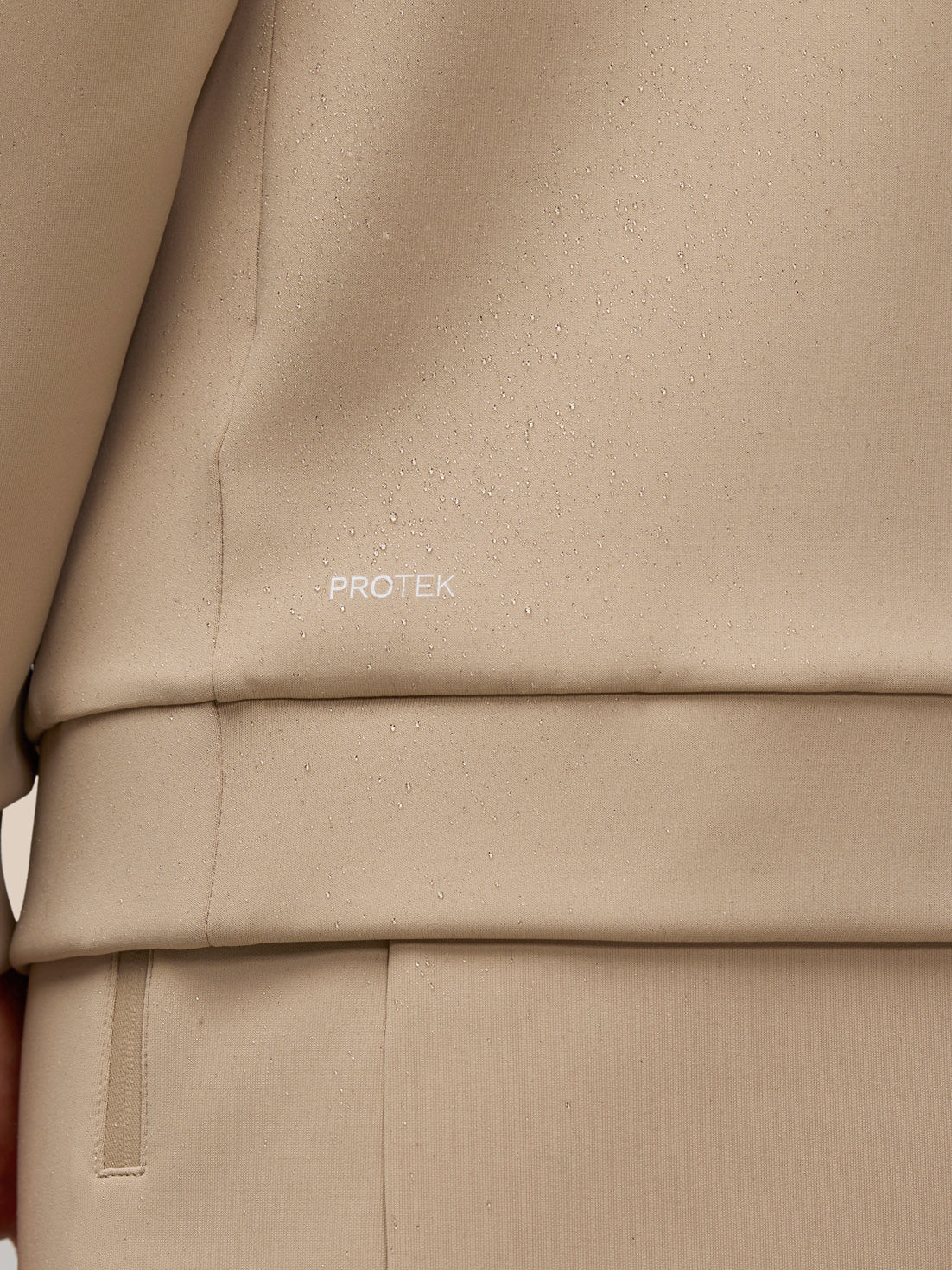 Close-up of beige fabric showing ProTek logo and water droplets on the surface.