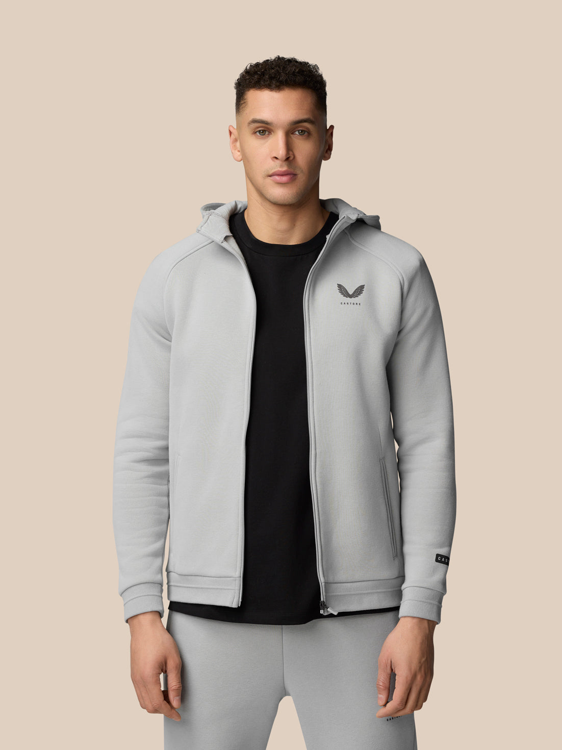 Close-up of a man wearing a light grey Adapt Fleece Zip-Through Hoodie showing the chest logo and zip