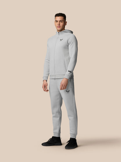 Full-body view of a model in grey Adapt Fleece Zip-Through Hoodie and matching joggers with Castore logos on chest and thigh.