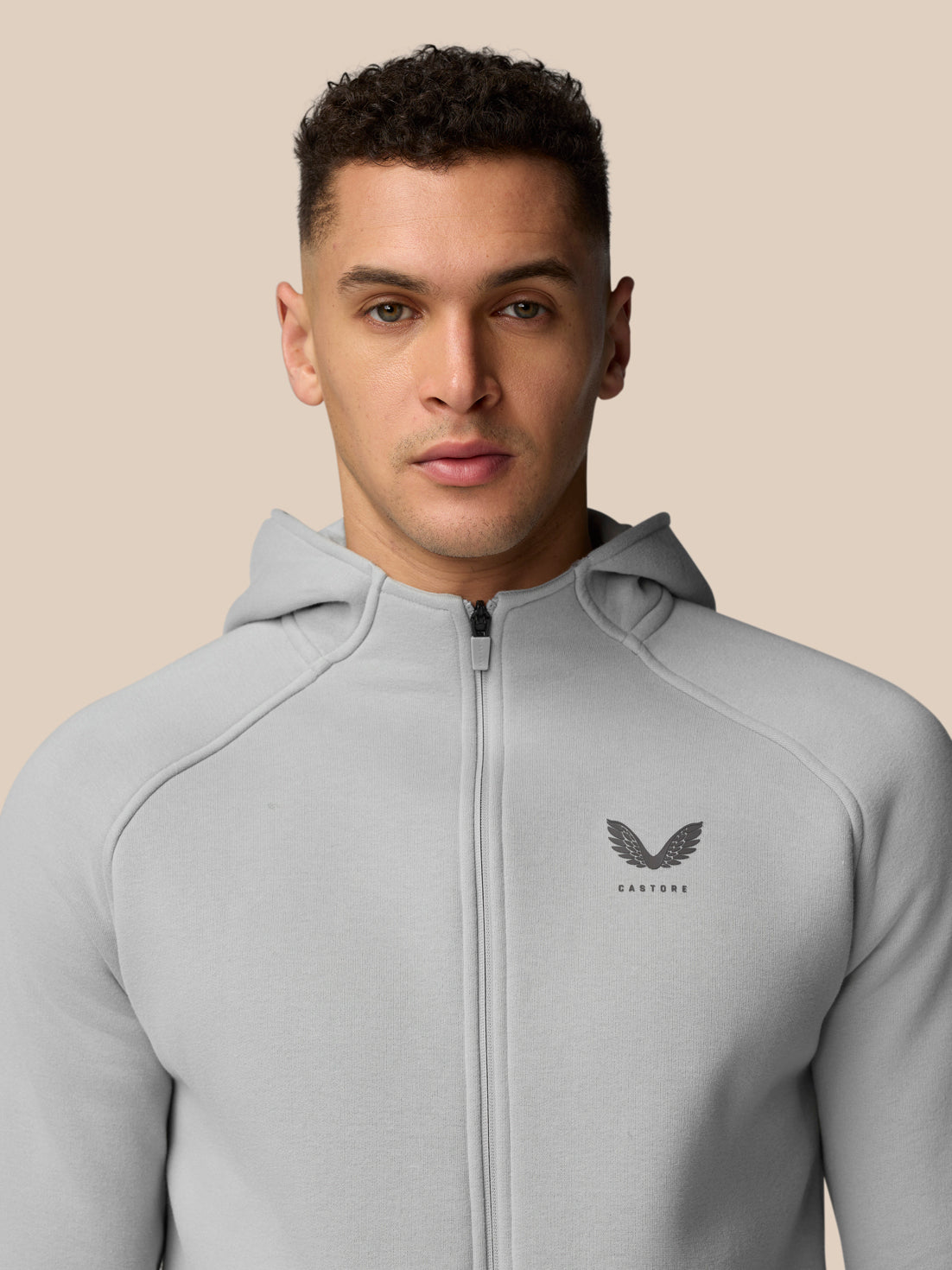 Front view of a man in a light grey Adapt Fleece Zip-Through Hoodie, zipped up with small chest logo