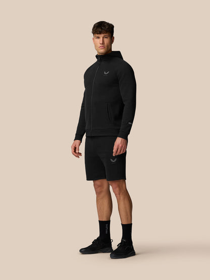 Full body view of male model in black Adapt Fleece Zip-Through Hoodie with hood and pockets