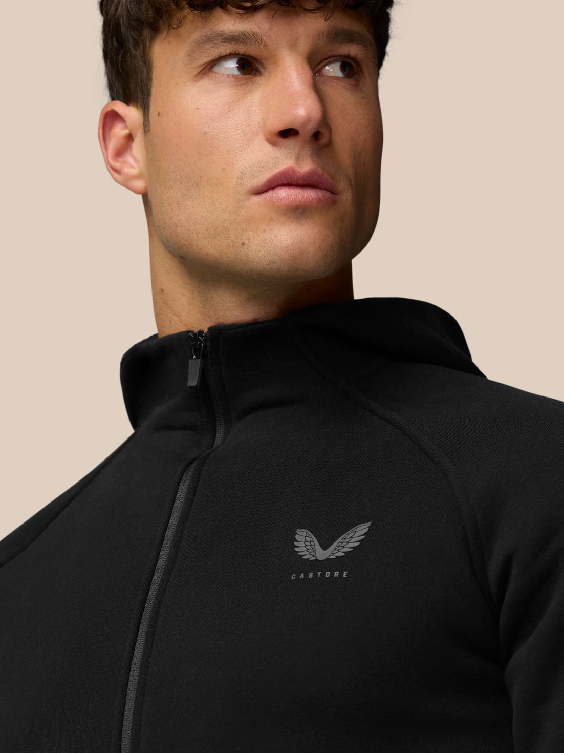Close-up of a man wearing black Adapt Fleece Zip-Through Hoodie with a high-build collar and Castore logo on the chest