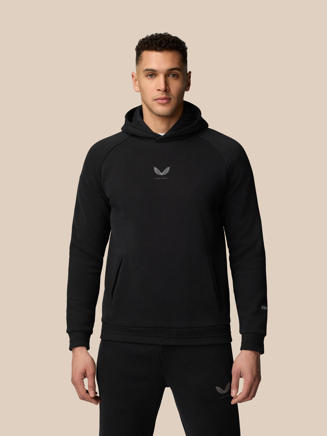 Model wearing black Adapt Fleece Hoodie with hood up, front pocket and chest logo.