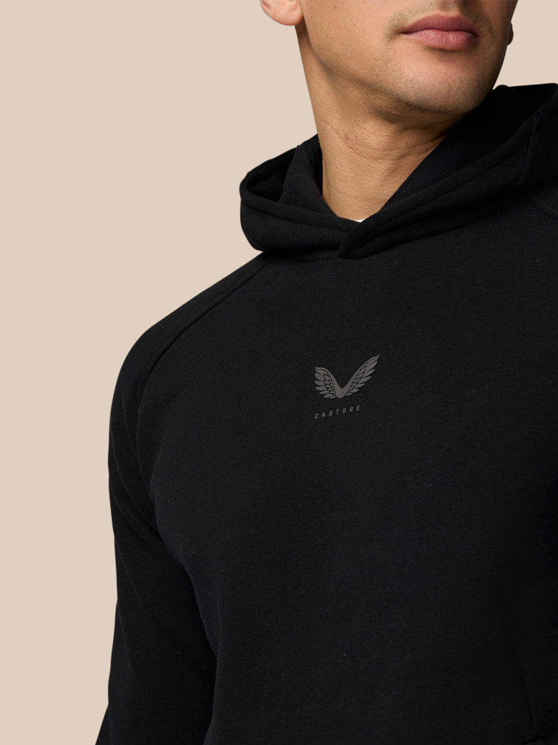 Close-up of upper torso and head wearing black Adapt Fleece Hoodie with hood up and small chest logo