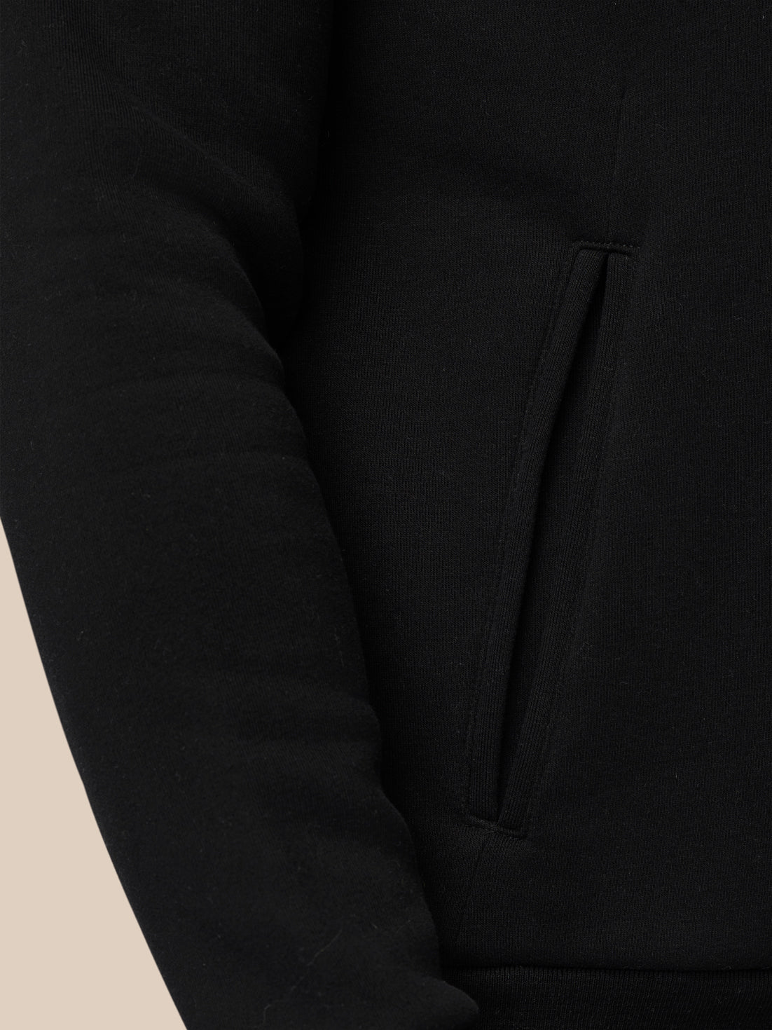 Close-up of black Adapt Fleece Hoodie pocket with vertical slit and visible stitching