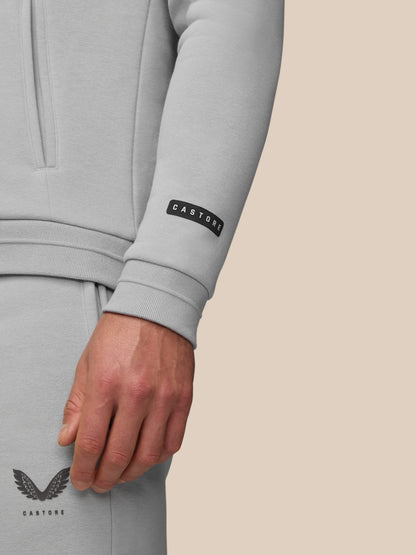 Model wearing grey Adapt Fleece Hoodie showing zip pocket and brand label on sleeve