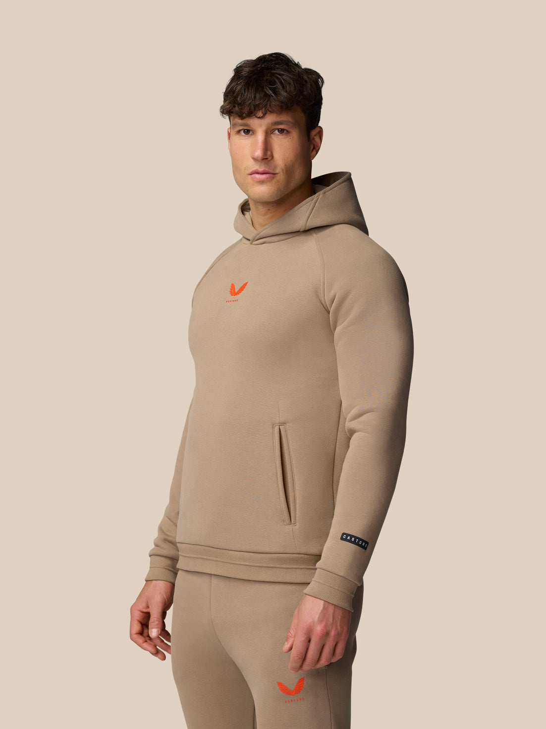 Model wearing Clay Adapt Fleece Hoodie with hood up showing front silhouette and chest logo.