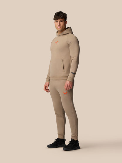 Full-body model wearing Adapt Fleece Hoodie in Clay with matching beige joggers