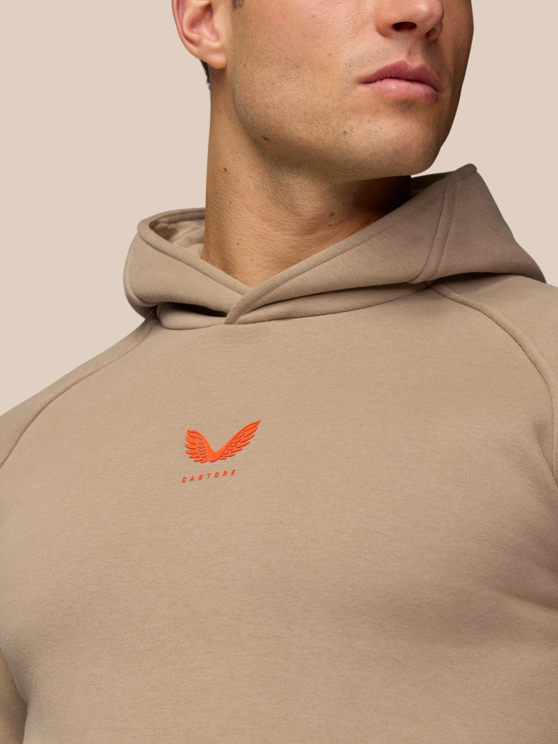 Close-up of Adapt Fleece Hoodie in Clay showing hood neckline and orange chest logo