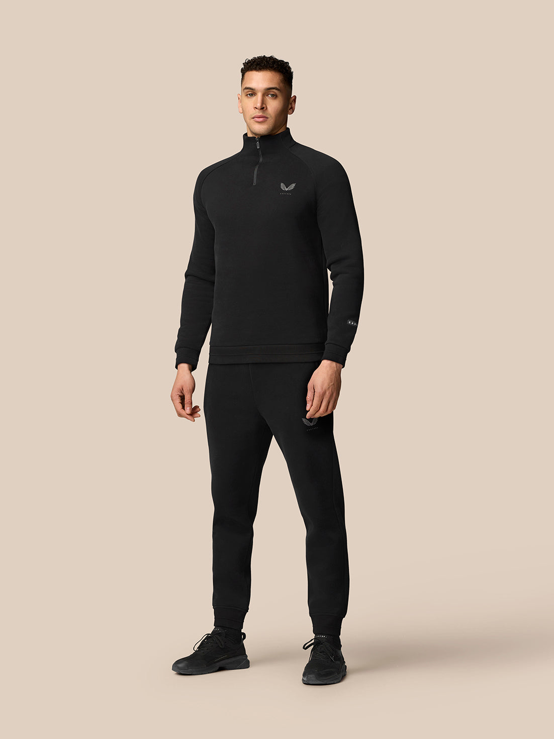 Model in black Adapt Fleece Quarter Zip with matching joggers, both featuring subtle logos for a coordinated look.