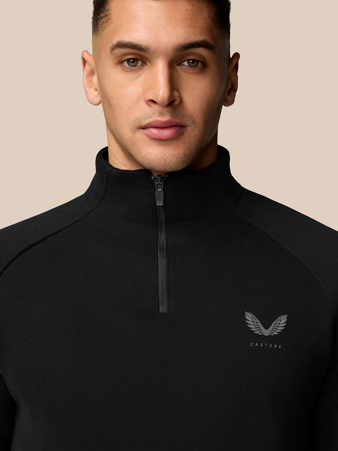 Close up of a man in a black quarter zip fleece with a high collar, front zipper, and CASTORE logo on the chest.