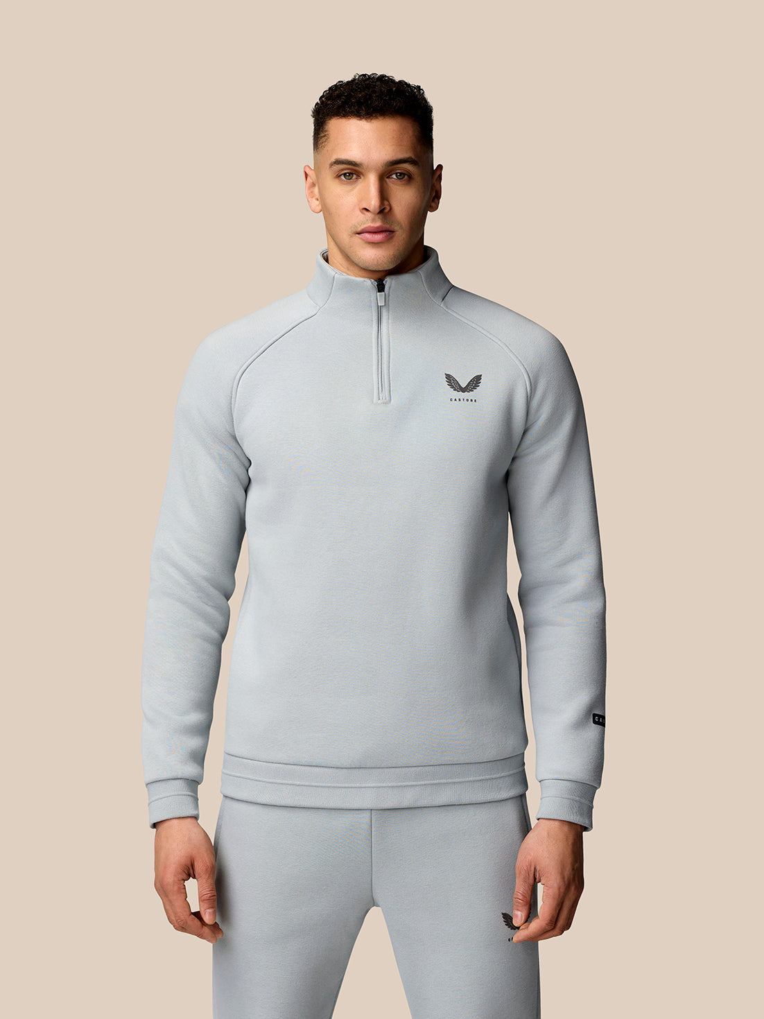 Man wearing light grey Adapt Fleece Quarter Zip with high collar and small chest logo