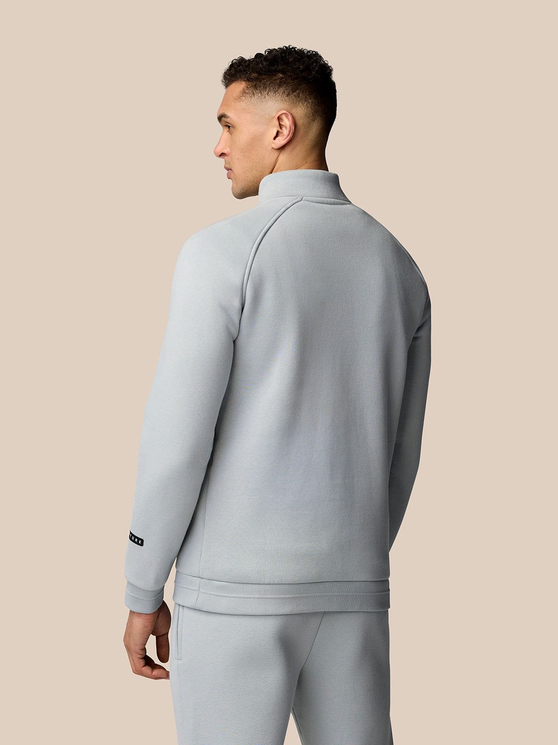 Back view of light grey Adapt Fleece Quarter Zip showing seam lines and sleeve logo patch