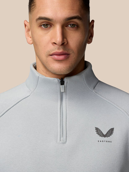 Close-up of a male model wearing a light grey Adapt Fleece Quarter Zip, highlighting the front zip and subtle chest logo.