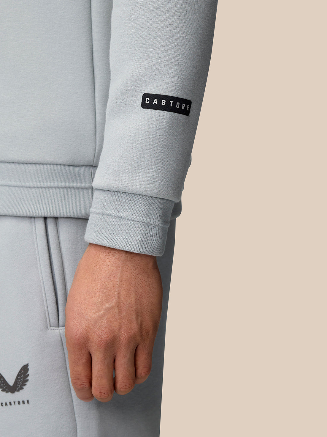 Close-up of the sleeve with a Castore tag on a light grey Adapt Fleece Quarter Zip.