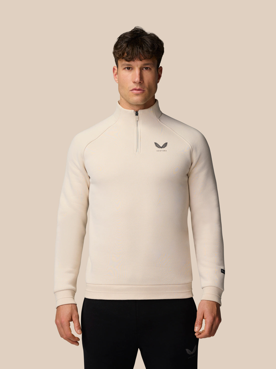 Male model in stone beige Adapt Fleece Quarter Zip with zip neck and subtle left chest logo