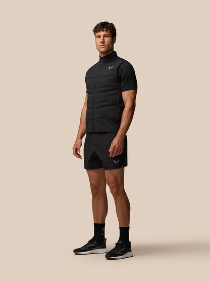 Full-body view of a male model wearing the black Zone Training Gilet over a black tee with matching shorts and sneakers