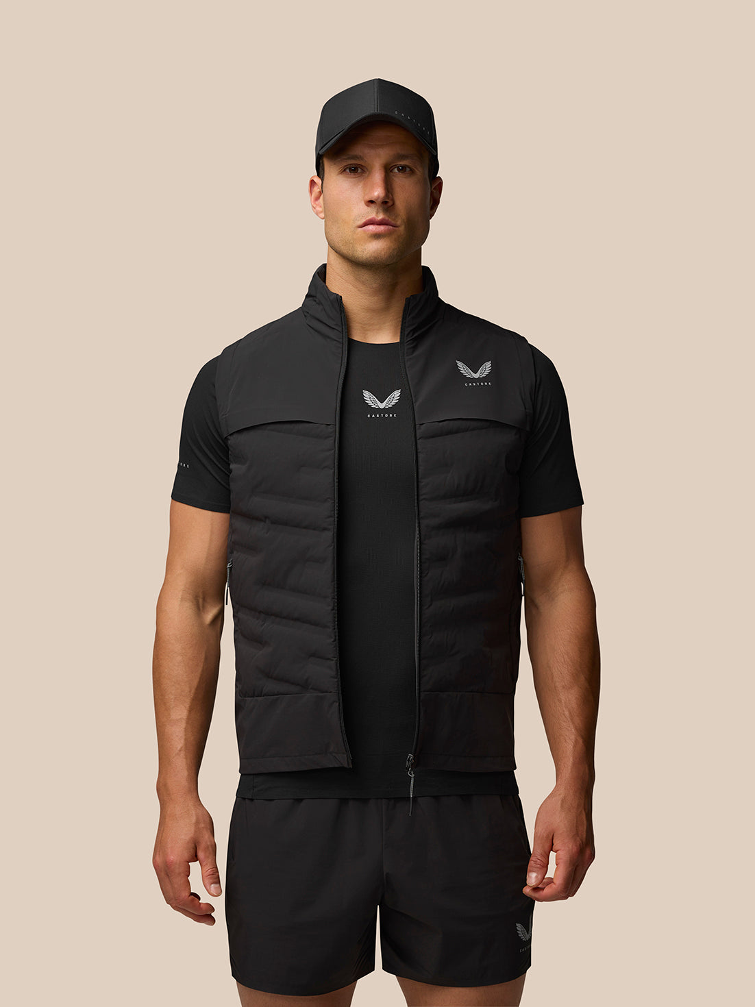 Male model wearing black Zone Training Gilet over a black top with cap and shorts.