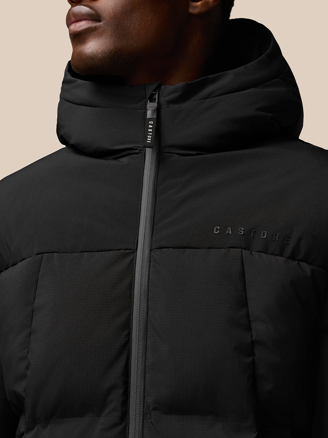 Close-up of black puffer jacket zipper with Castore branding on the chest.