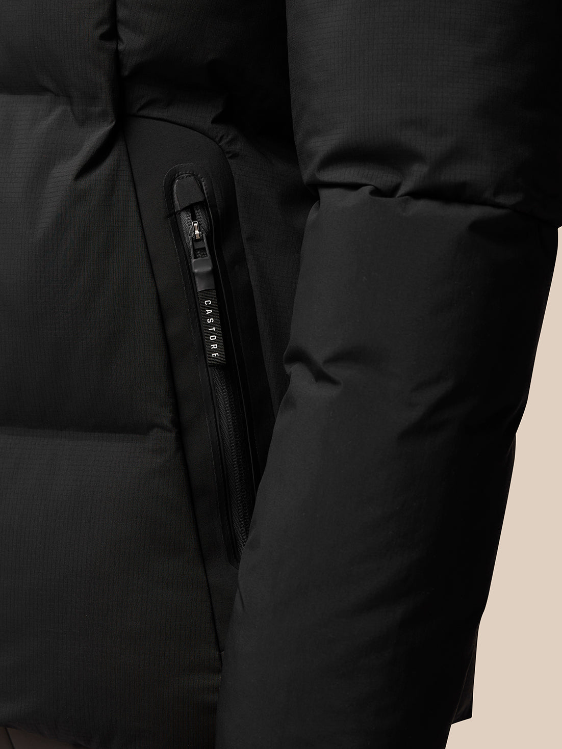 Close-up of front zipper and Castore branded zipper pull on a black puffer jacket.