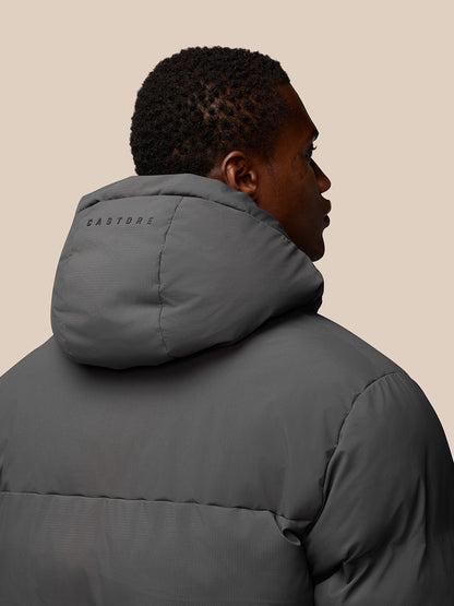 Rear three-quarter view of model in charcoal puffer jacket with hood, CASTORE branding on the hood.