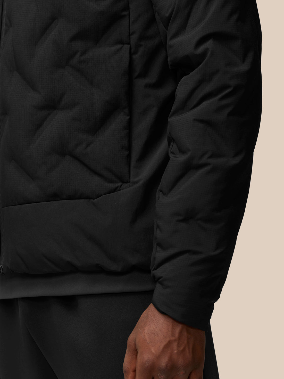 Close-up of black padded jacket torso with a pocket and visible sleeve.