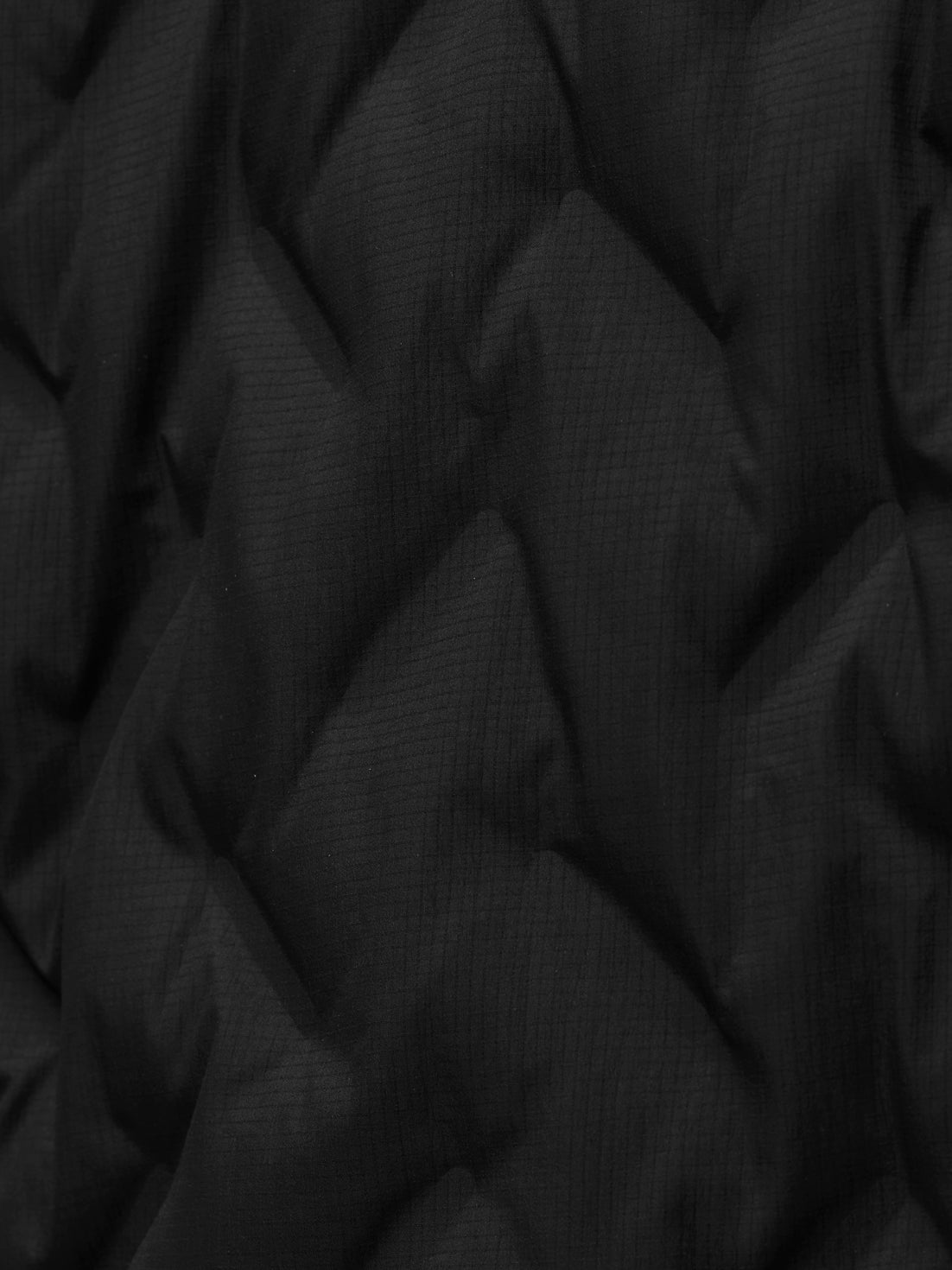 Close-up of black textured jacket fabric with a subtle grid pattern and folds.