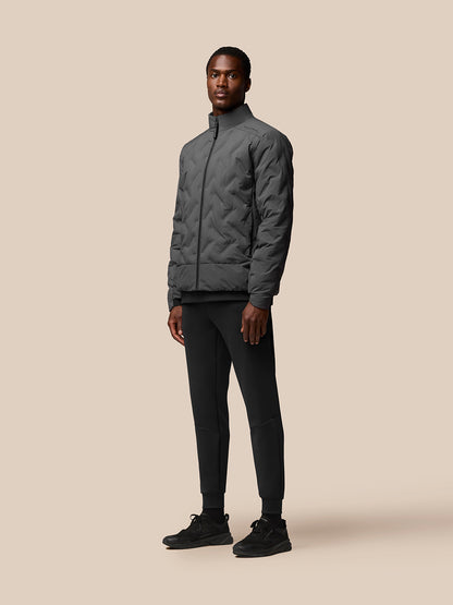 Male model wearing charcoal padded jacket with stand collar and full front zip.