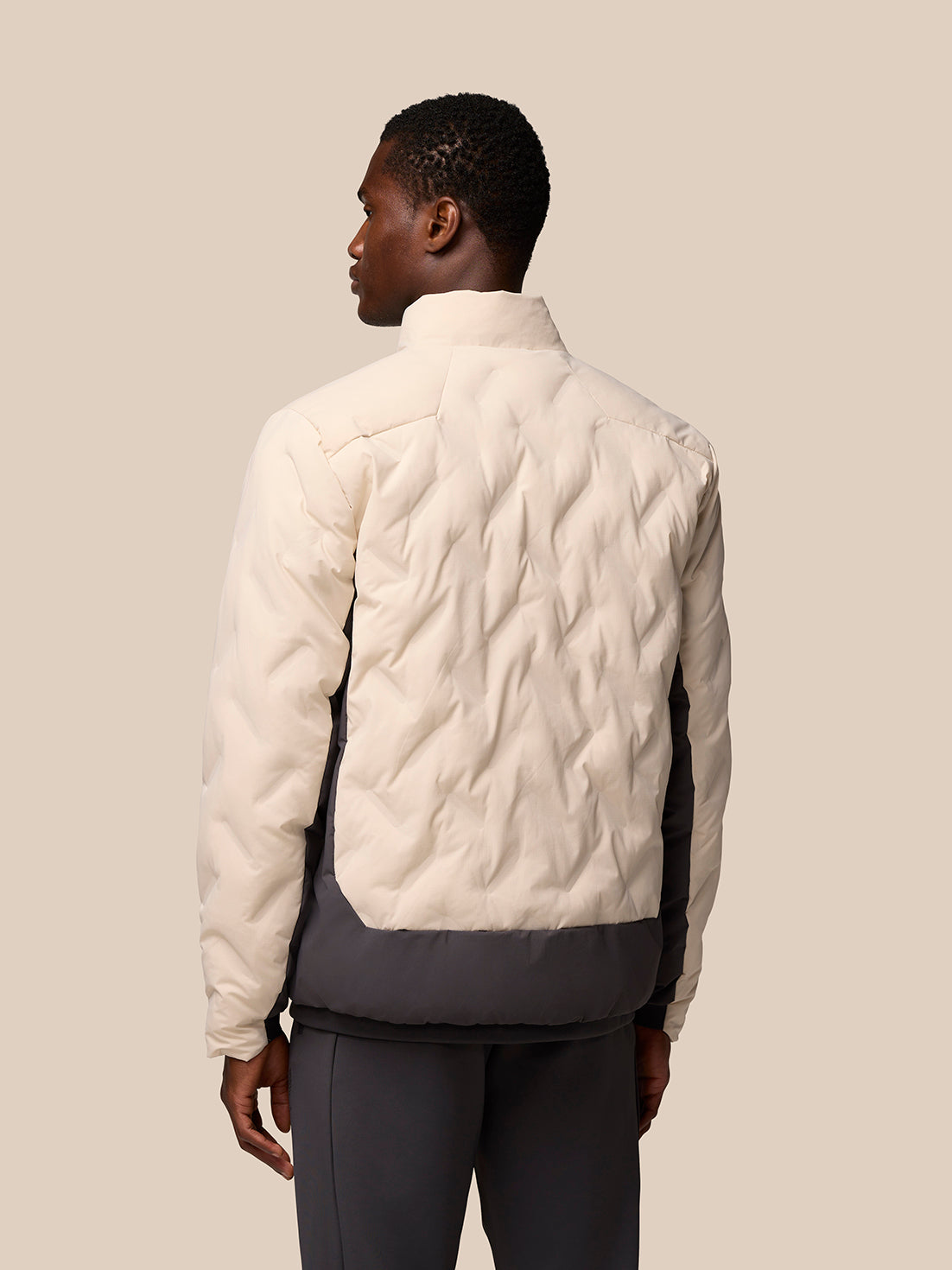 Back view of beige two-tone padded jacket with light upper panels and dark lower hem