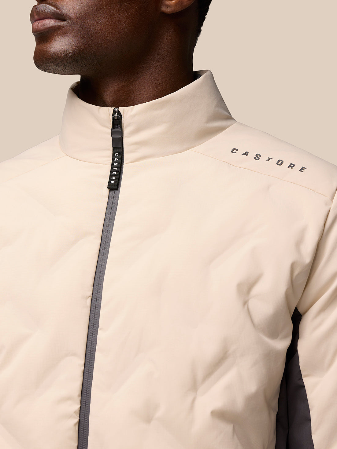 Front view of beige padded jacket with center zipper and high collar; CASTORE branding on the shoulder