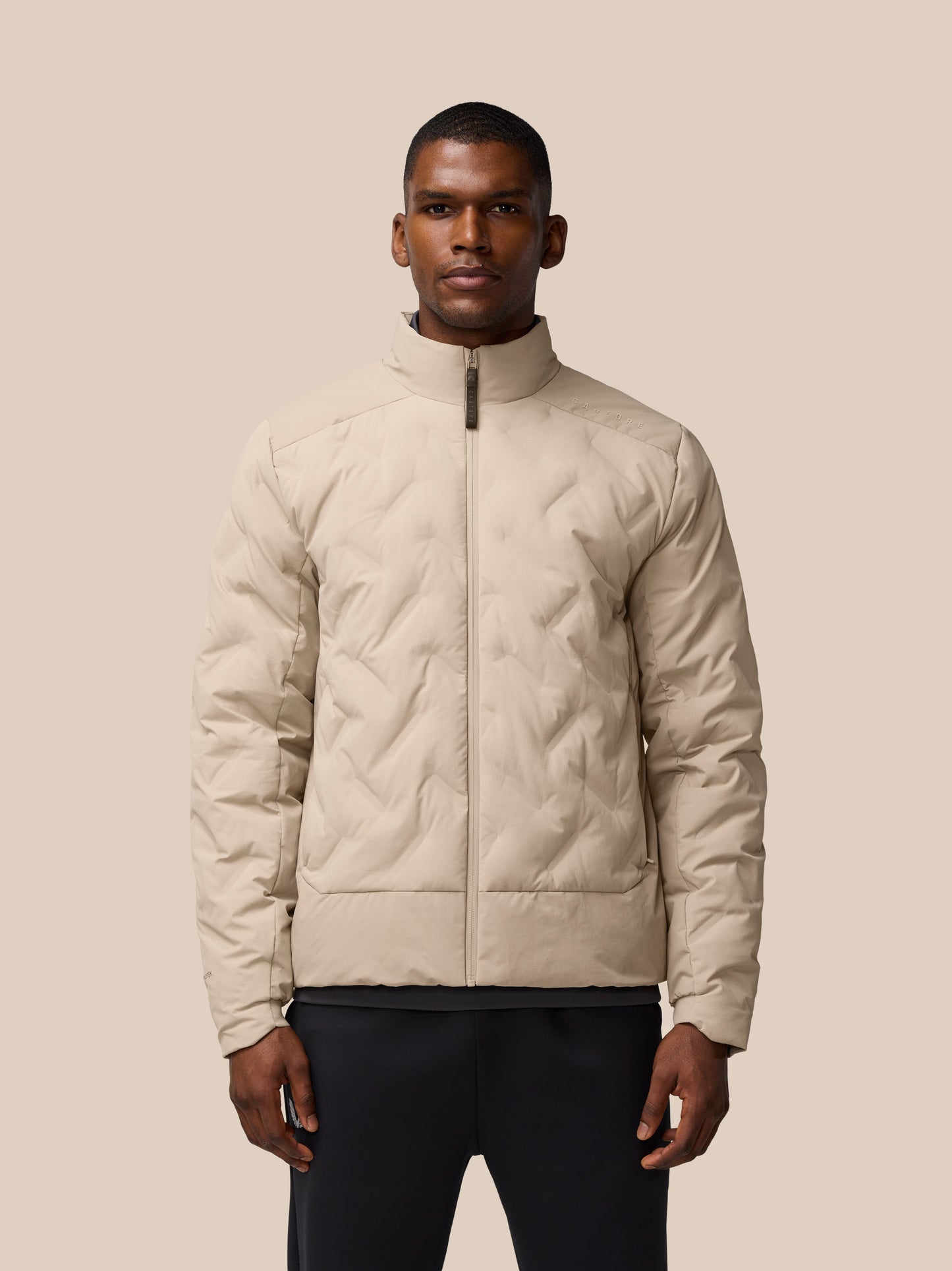 Man wearing mushroom colored padded jacket with zip front and high collar