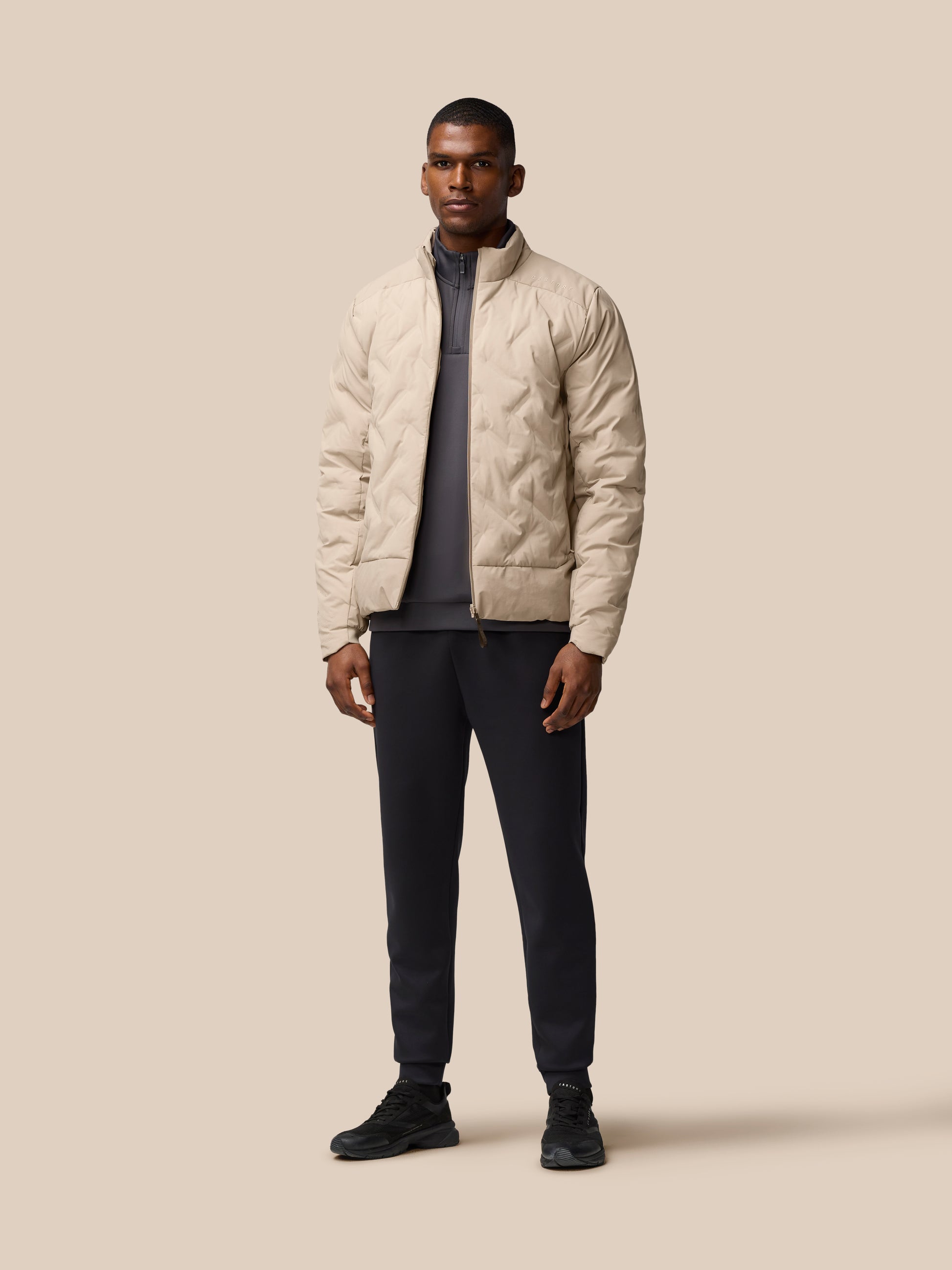 Male model wearing mushroom beige padded jacket with zip front and stand up collar