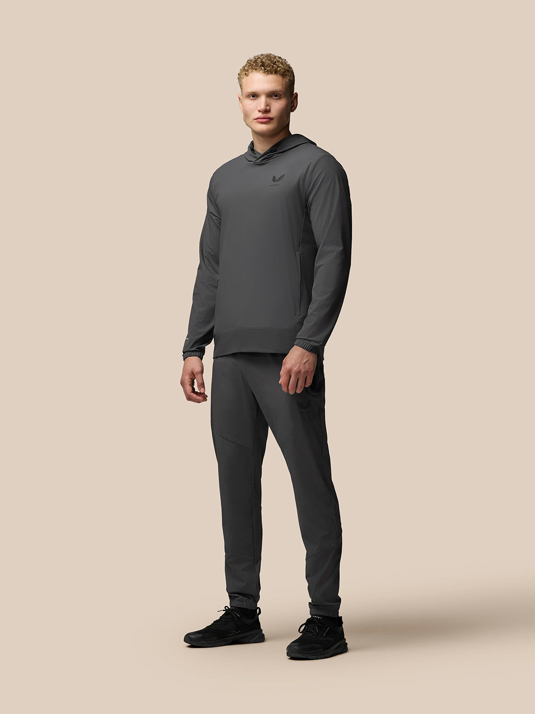 Male model wearing grey Lightweight Flex Hoodie with matching joggers and chest logo