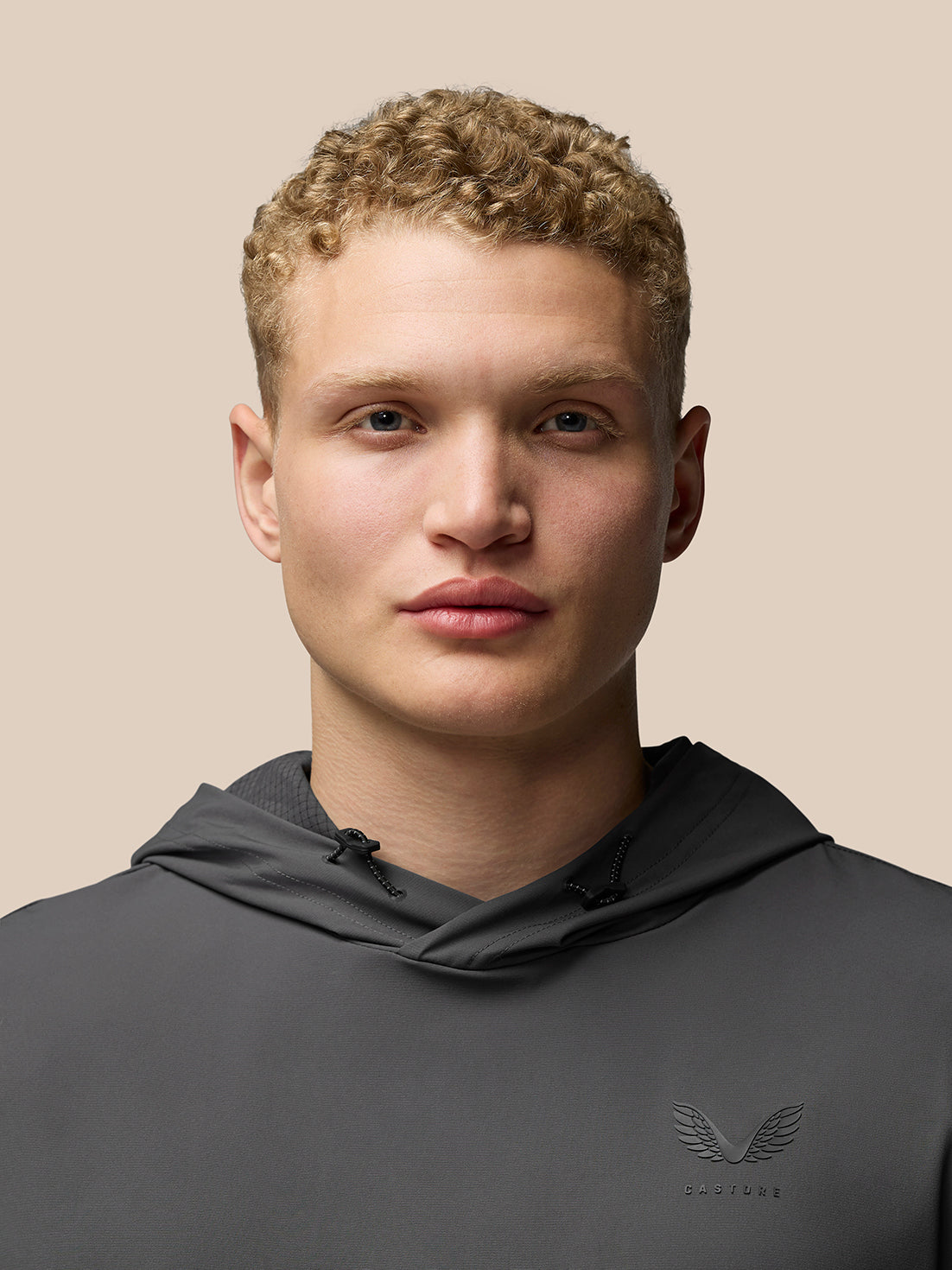 Close up of a grey hoodie on a model showing drawstrings and the chest logo