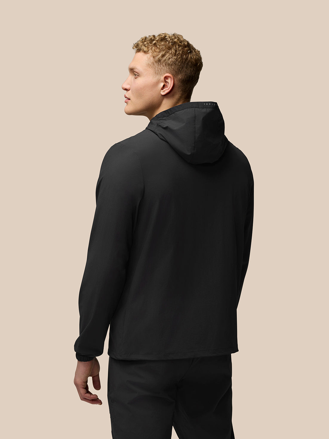 Back view of a man wearing a black Flex Lifestyle Jacket with hood