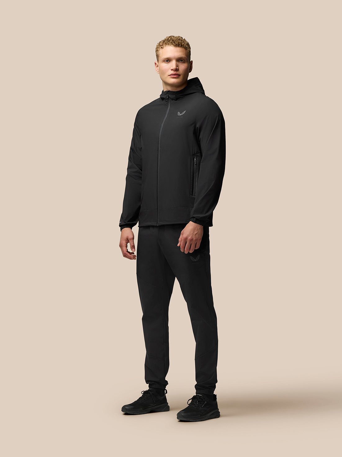 Full body shot of a man in a black hooded Flex Lifestyle Jacket with matching pants